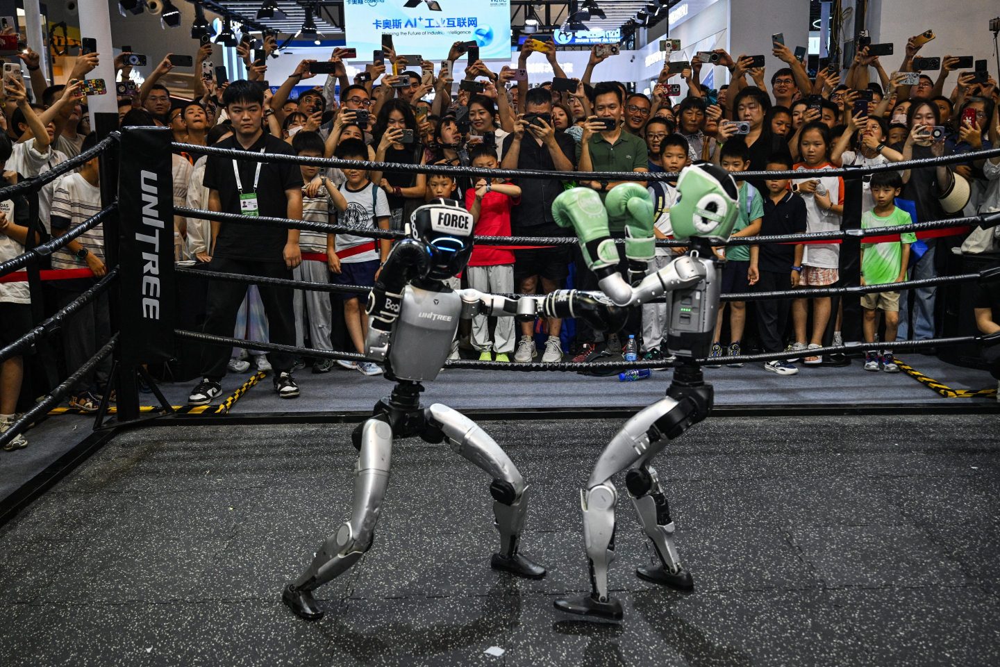 People watch remote-controlled robots by Unitree Robotics boxing during the World Artificial Intelligence Conference (WAIC) at the Shanghai World Expo and Convention Center in Shanghai on July 28, 2025.