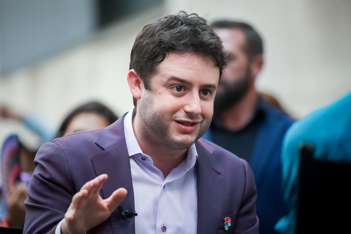 Figma CEO Dylan Field wearing a purple jacket and waving