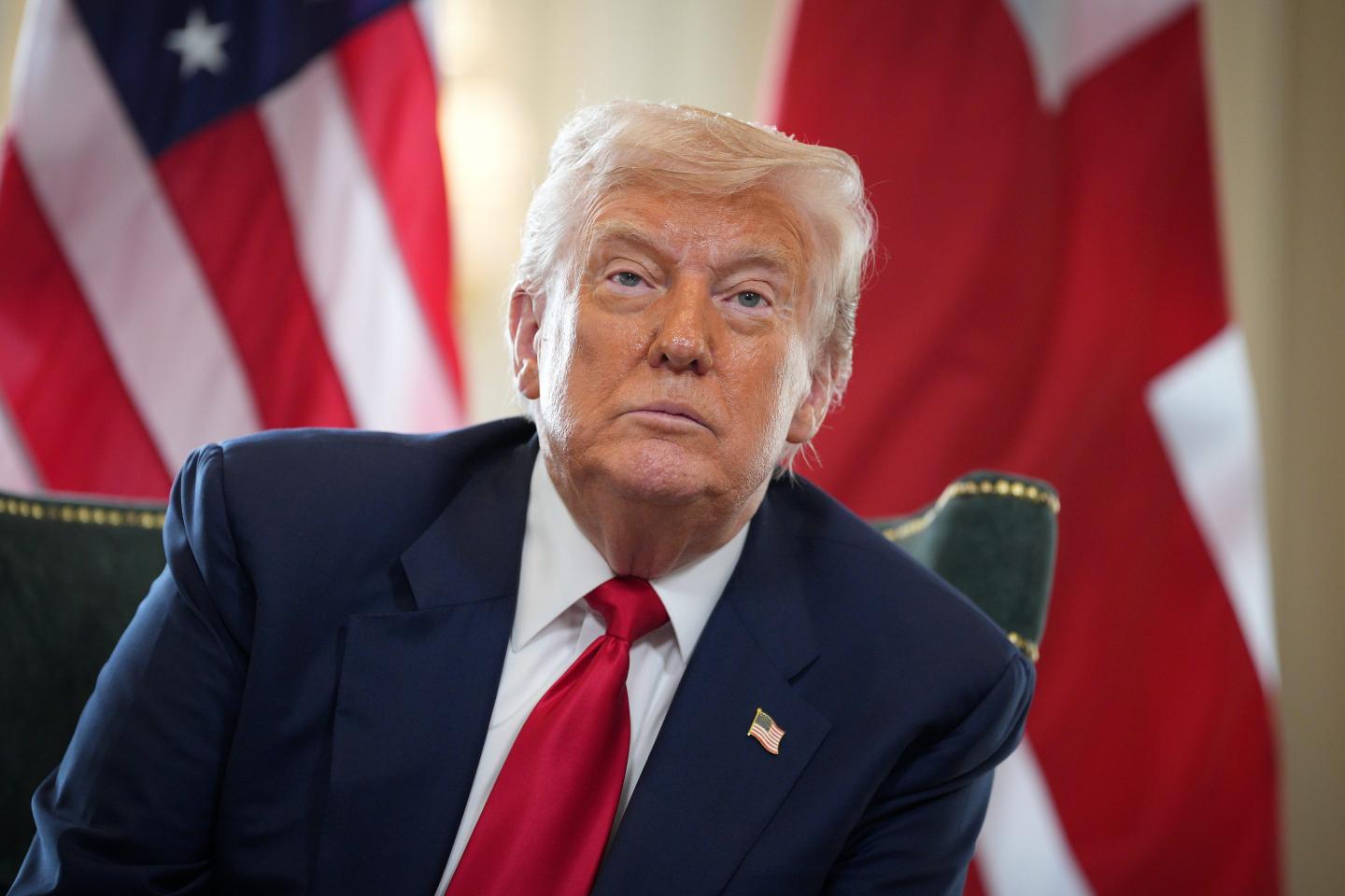 Donald Trump sitting in front of an American flag