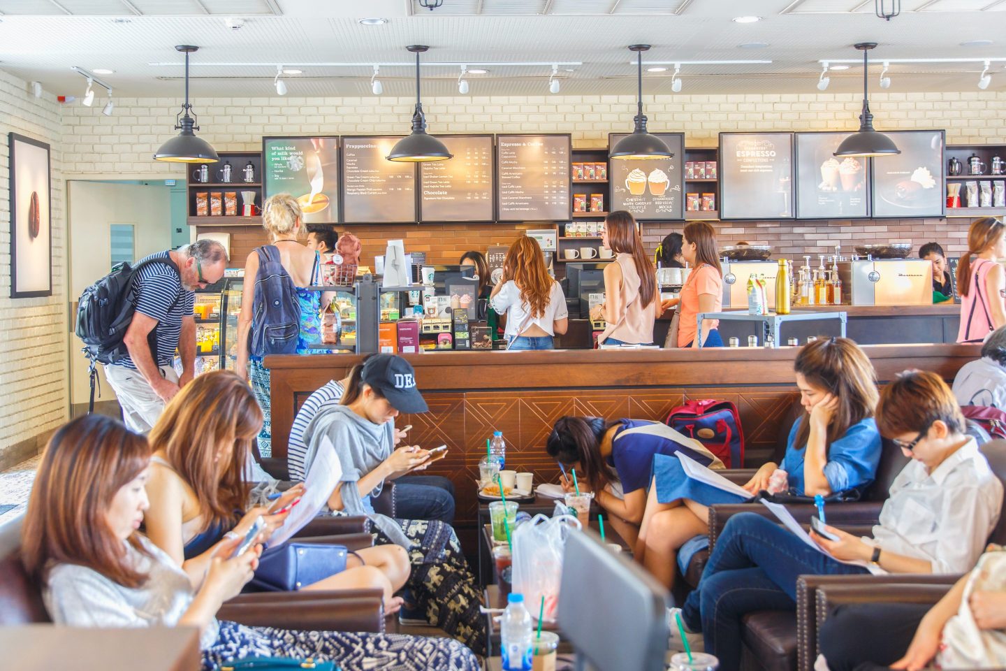 A group of young people fill tables and seats of a Starbucks cafe