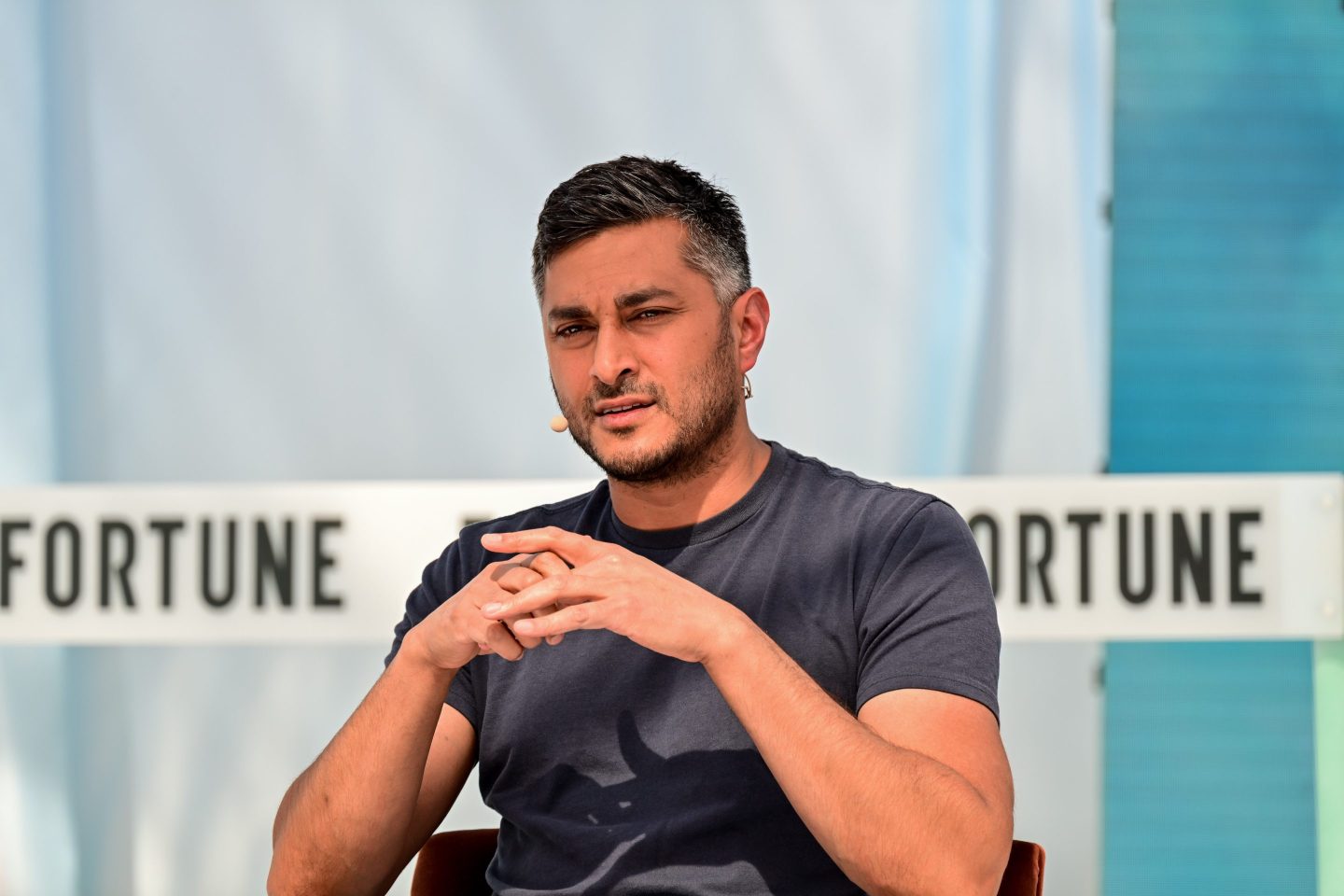 Arjun Sethi looks at the camera on stage on a panel.