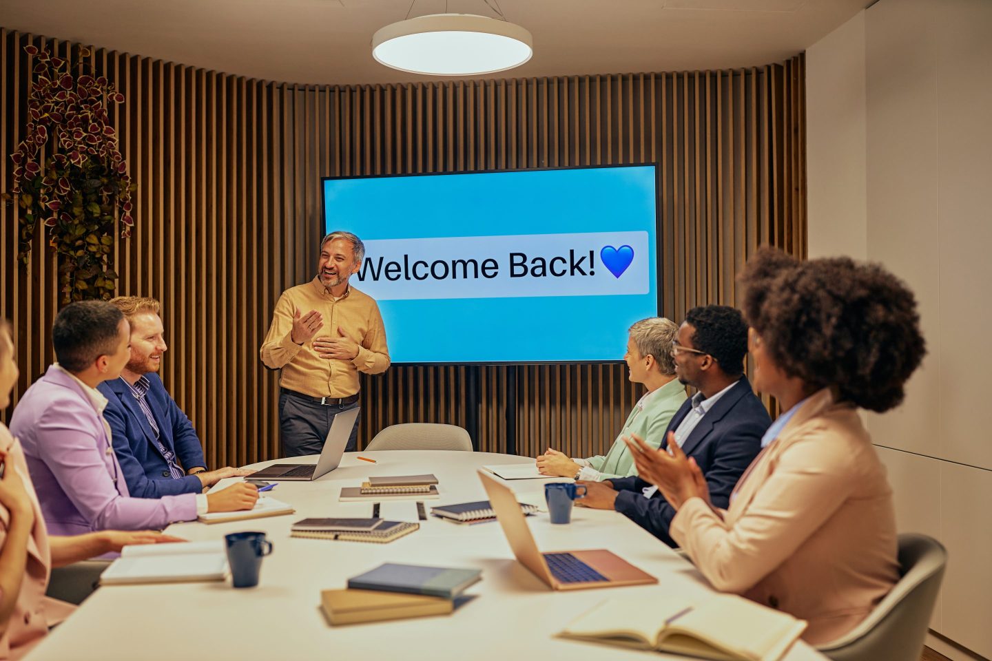 Employees in meeting with "Welcome Back" on screen