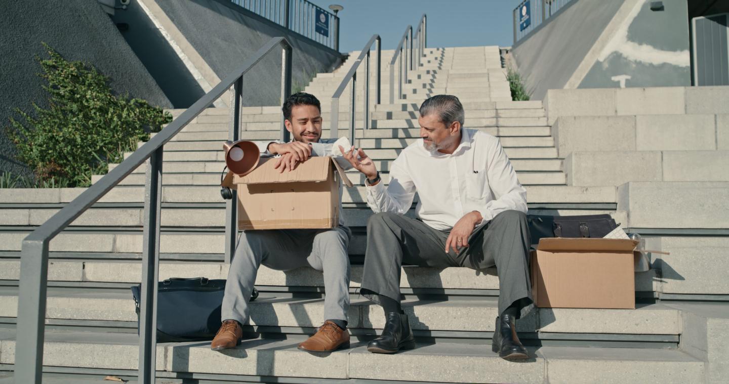 Two employees who quit sit on steps and talk