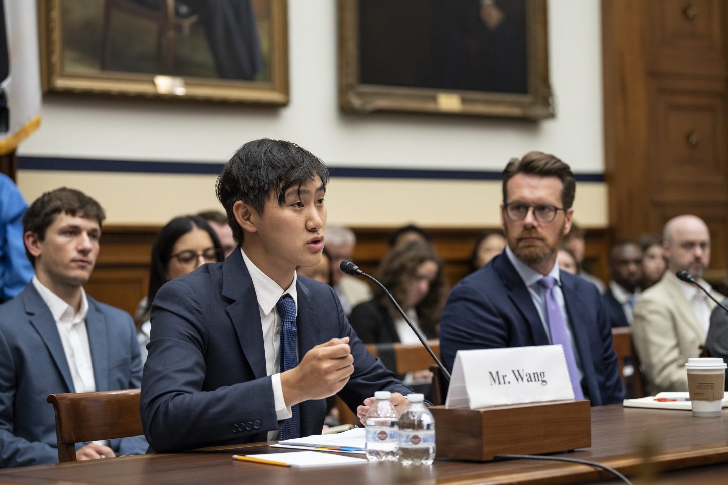 At left, CEO of Scale A.I. Alexandr Wang testifies during a House Armed Services Subcommittee on Cyber, Information Technologies and Innovation hearing about artificial intelligence, as other people watch him, on Capitol Hill July 18, 2023 in Washington, DC