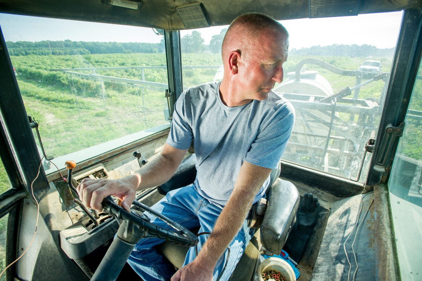 A farmer in a tractor looks down at his field.