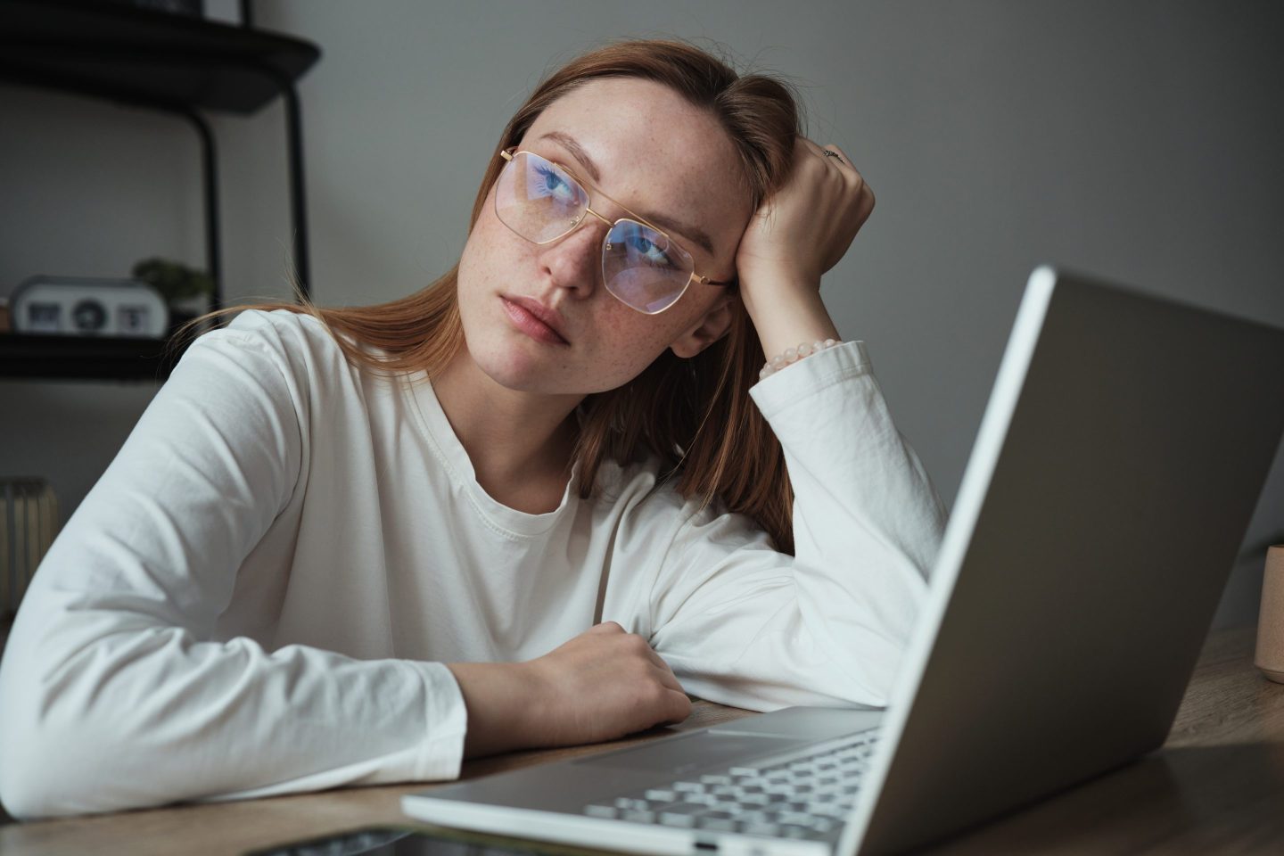 Woman leans on her wrist, laptop in front