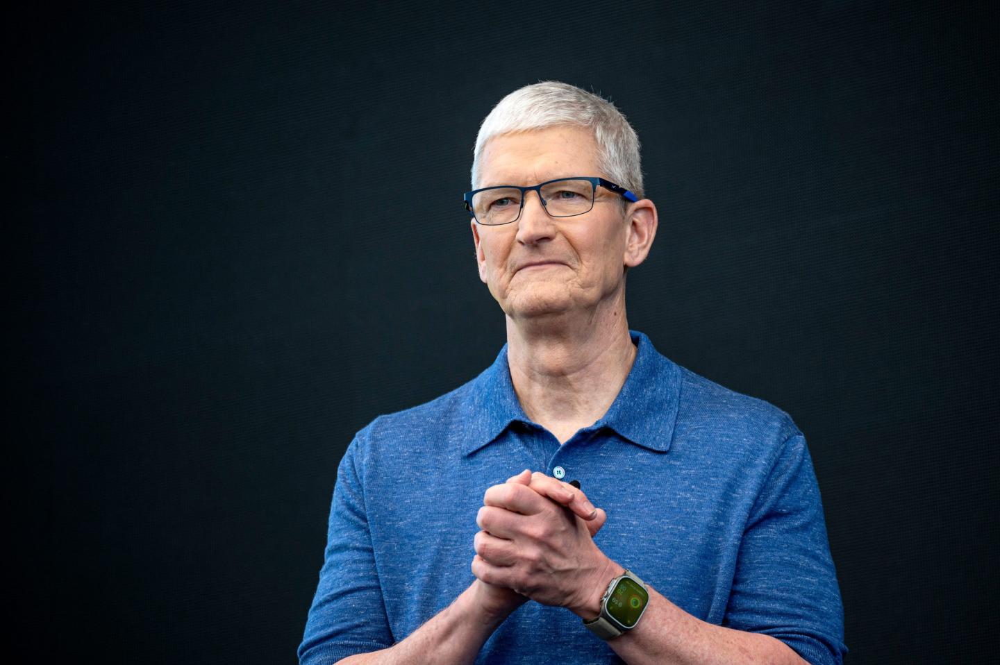Tim Cook clasps his hands, looking solemn