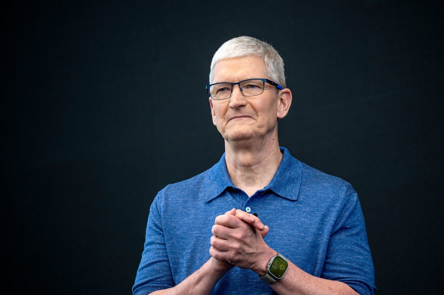 Tim Cook clasps his hands, looking solemn