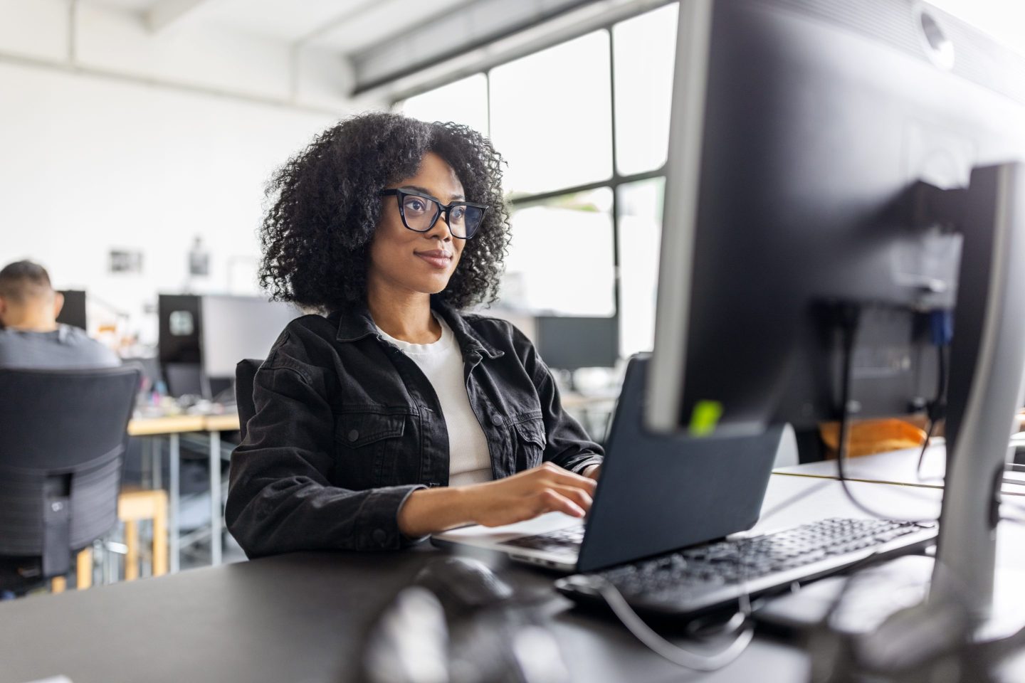A woman sits at a computer in an office.