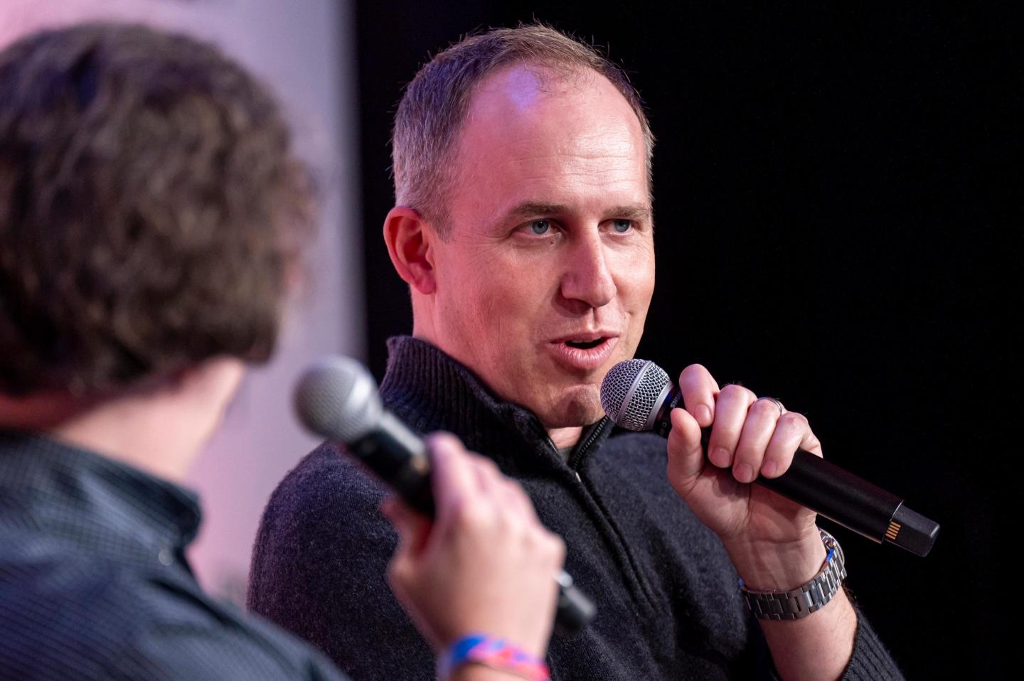 Bret Taylor speaks into a microphone he is holding.