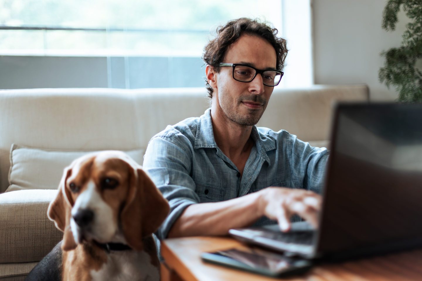 Mid-aged man comfortably working at home sitting on the floor with his Beagle dog by his side