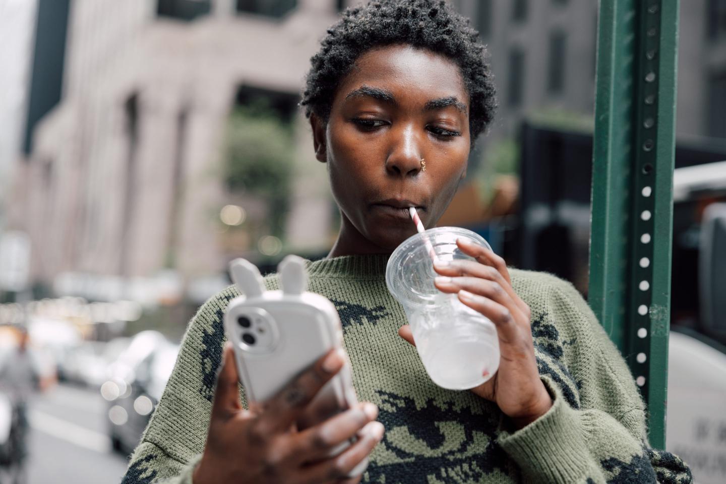 A Gen Zer sipping a soda, looking at their phone