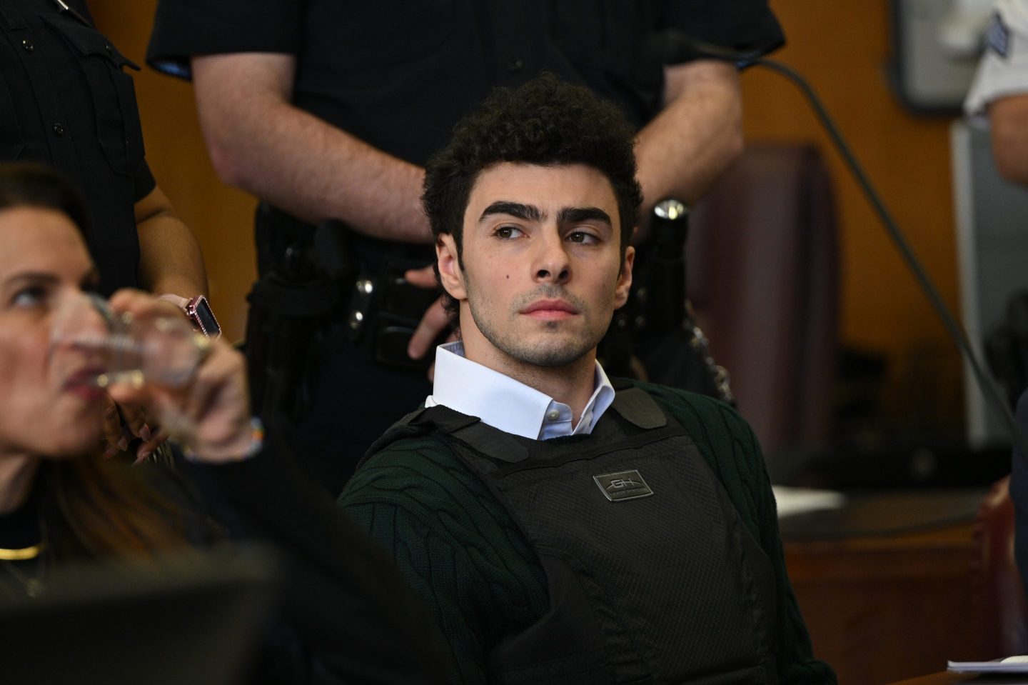 Luigi Mangione, in a collered shirt with a sweater over it, appears at a hearing for the murder of UHC CEO Brian Thompson at Manhattan Criminal Court on February 21, 2025 in New York City.