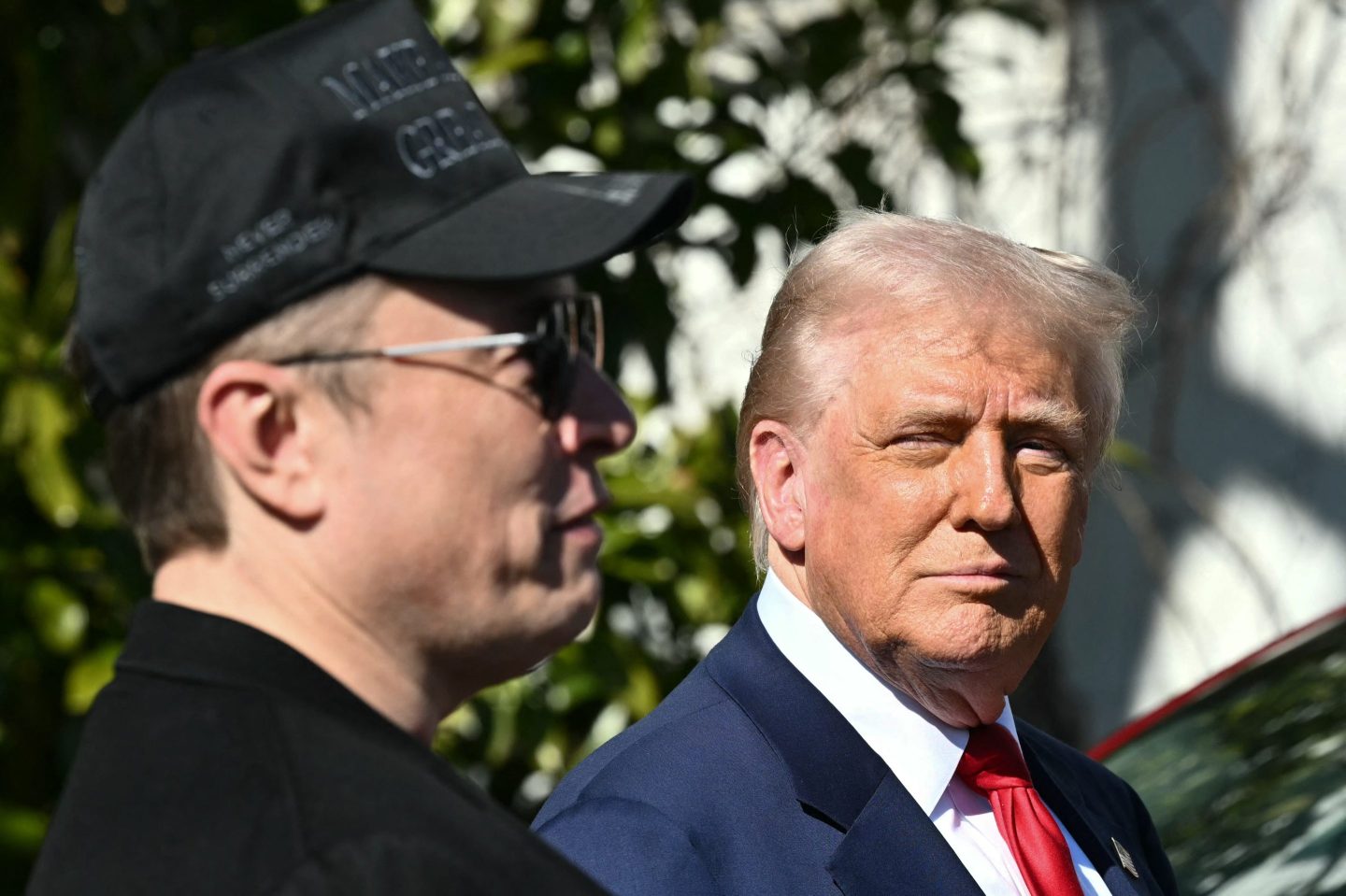 US President Donald Trump squints at Tesla CEO Elon Musk as tey speak to the press as they stand next to a Tesla vehicle on the South Portico of the White House on March 11, 2025 in Washington, DC. (