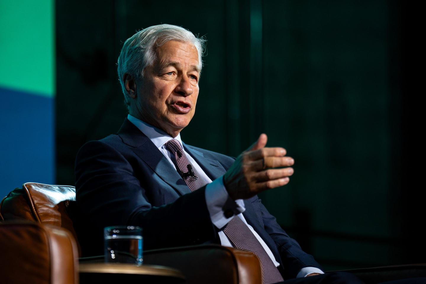 Jamie Dimon, sitting on stage, gestures with one hand as he speaks.
