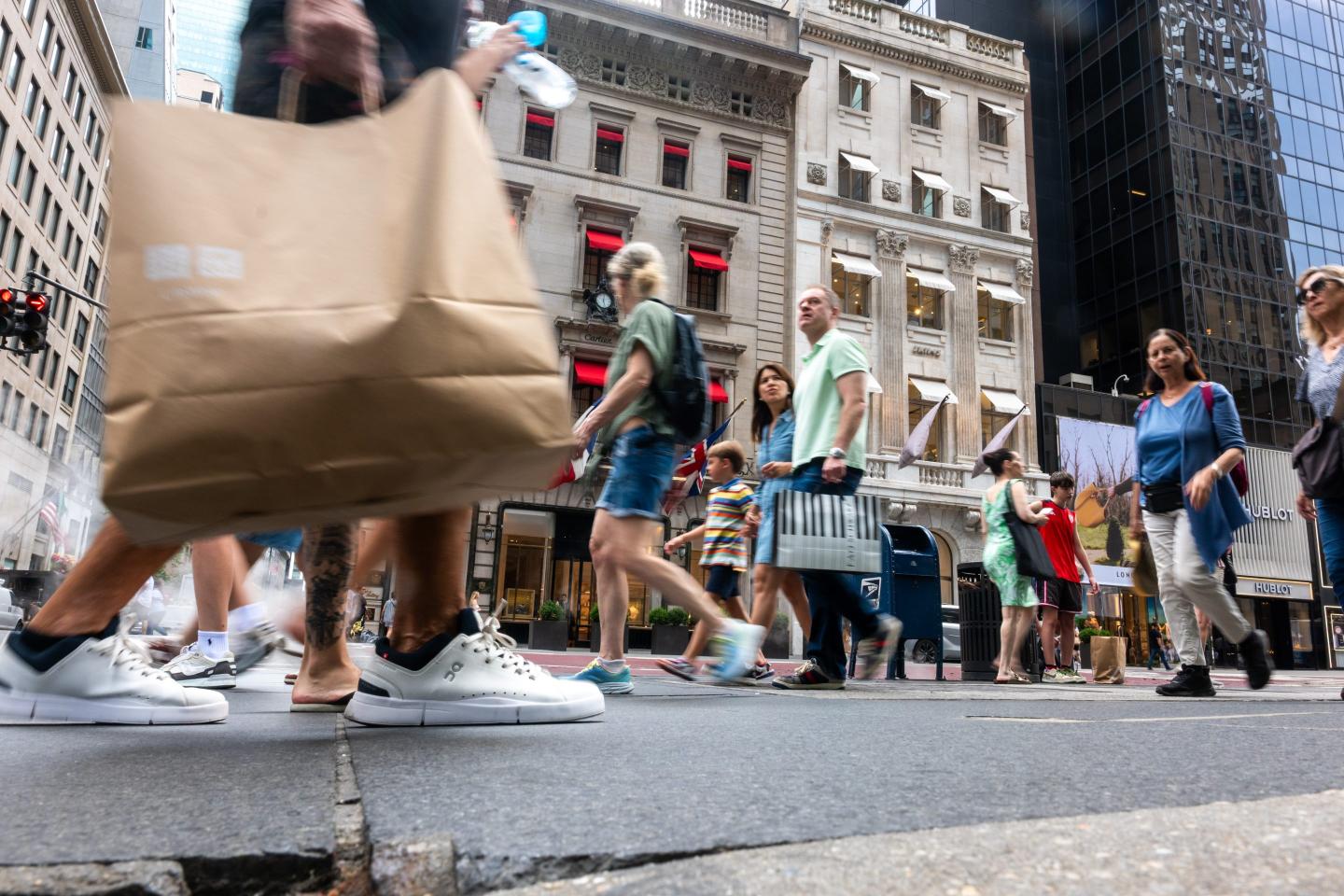 People walk in a shopping district along 5th Avenue in Manhattan on July 14, 2025, in New York City.