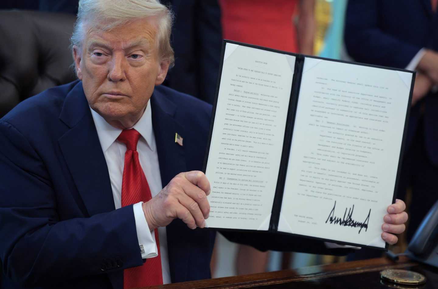 U.S. President Donald Trump signs executive orders in the Oval Office at the White House on August 25, 2025 with a bruise on the back of his hand.