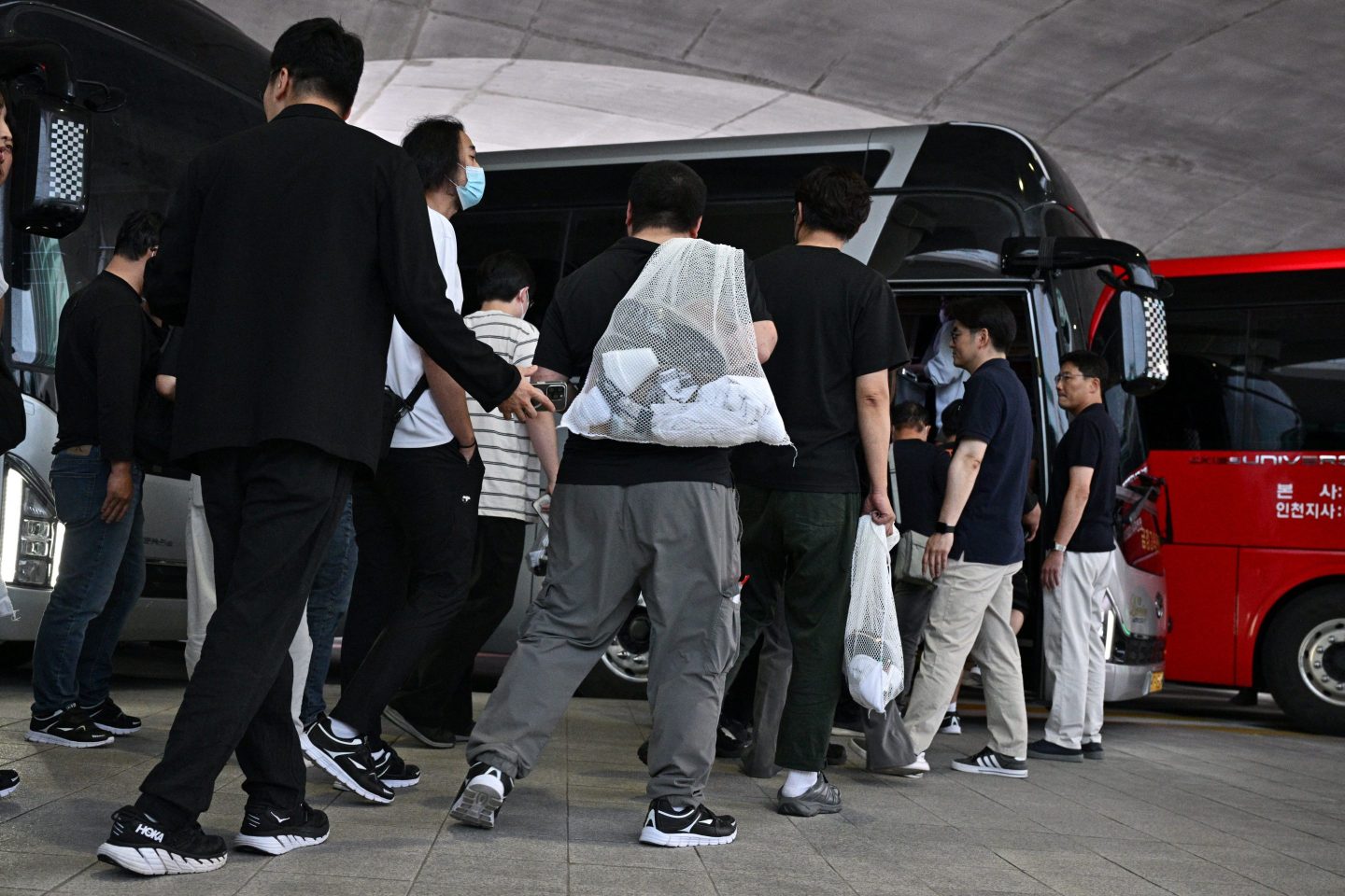 South Korean board coaches at Incheon International Airport on Friday after their detention in a US immigration raid at a Hyundai-LG plant in Georgia.