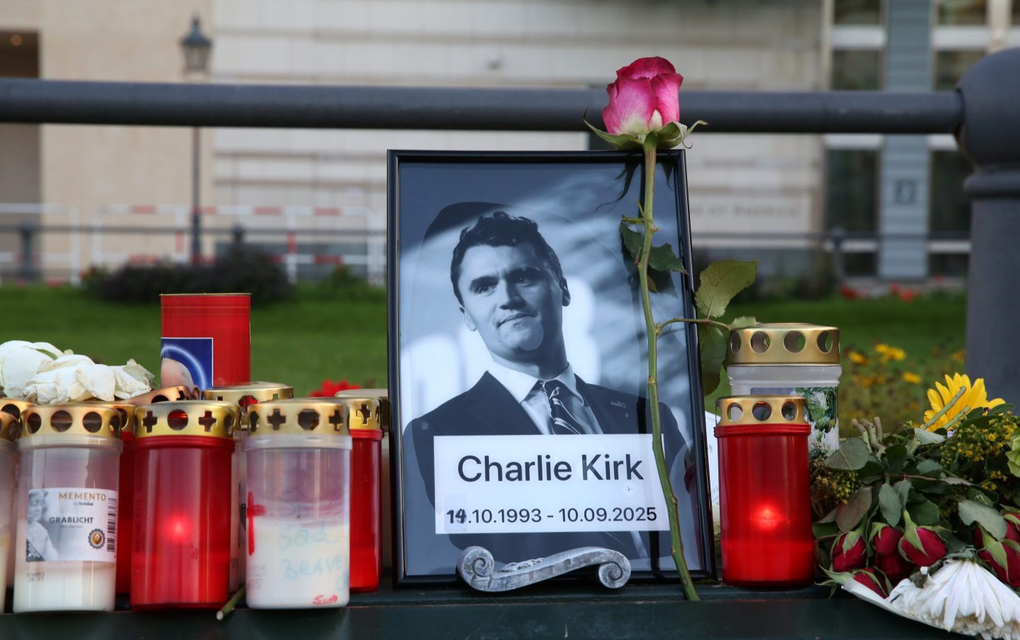 Flowers and candles are seen at a makeshift memorial for murdered American conservative activist Charlie Kirk outside the U.S. embassy as its flag hangs at half-staff on September 14, 2025 in Berlin, Germany.