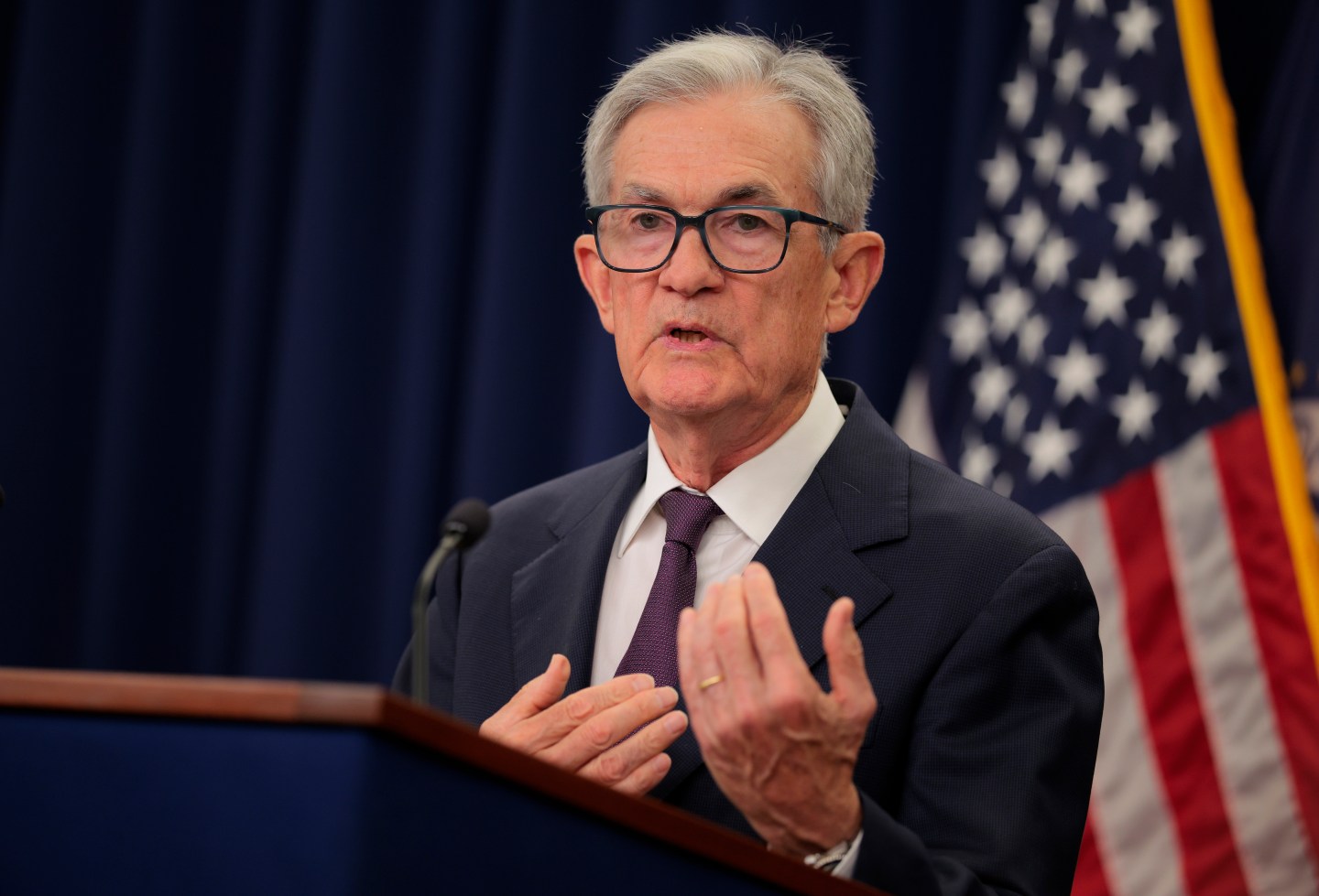 Federal Reserve Chair Jerome Powell in a dark suit at a podium.