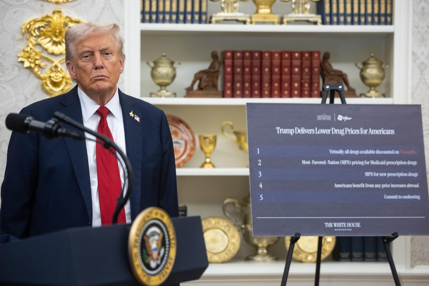 US President Donald Trump near a sign on lowering drug prices in the Oval Office of the White House in Washington, DC, US.