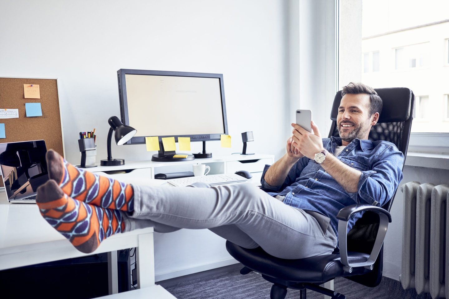 Business man props his feet up on an office table, with no shoes on