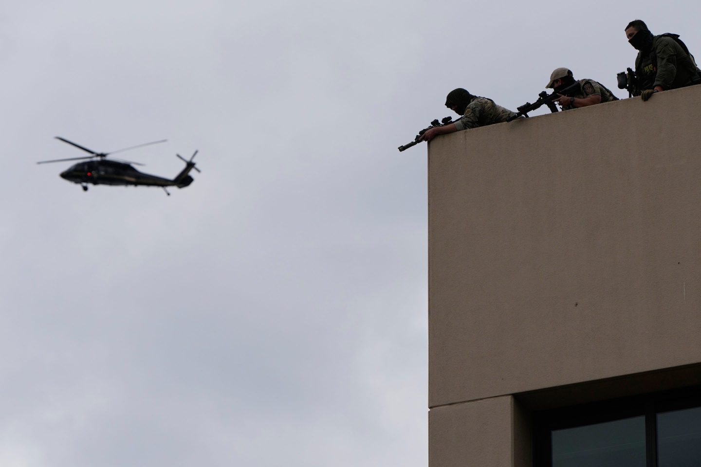 Law enforcement agents aim their weapons from the roof of a U.S. Immigration and Customs Enforcement facility as a helicopter flies past during a protest on Saturday in Portland, Ore.