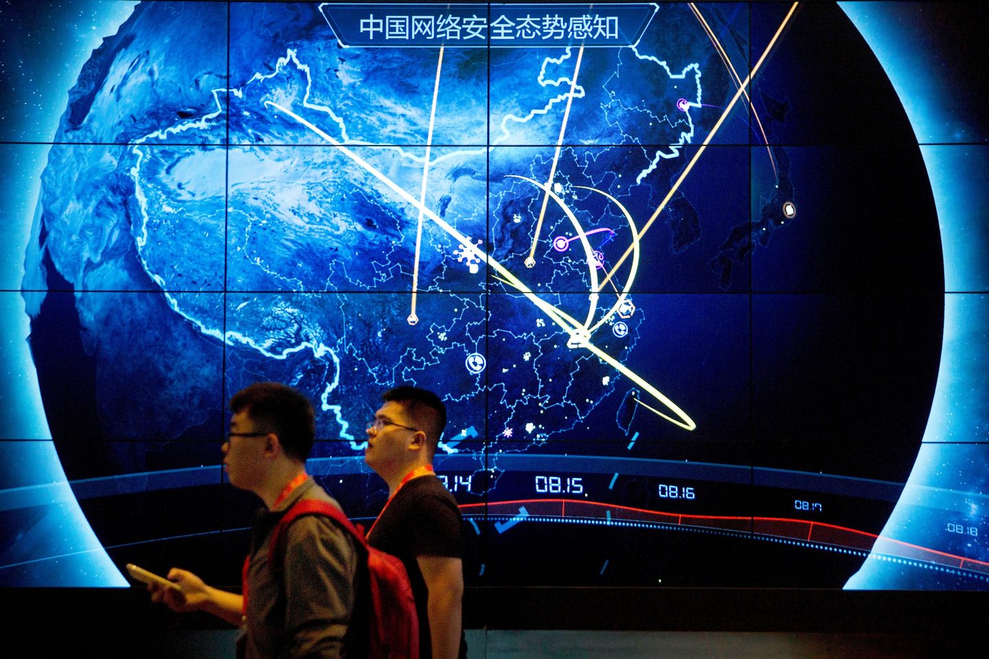 Attendees walk past an electronic display showing recent cyberattacks in China at the China Internet Security Conference in Beijing on Sept. 12, 2017.