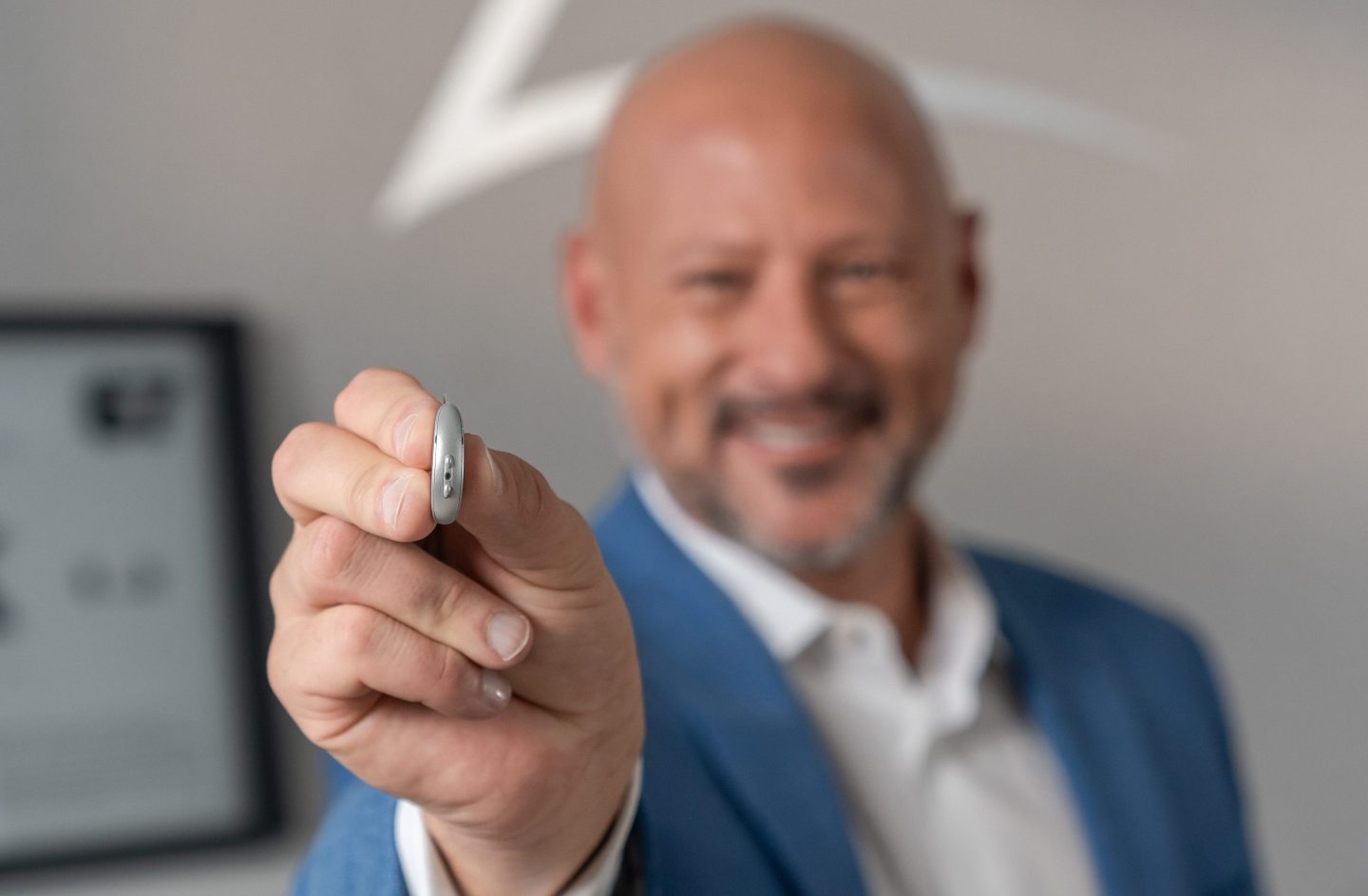 Brandon Sawalich, president and CEO of Starkey, holds the new Omega AI hearing aid model.