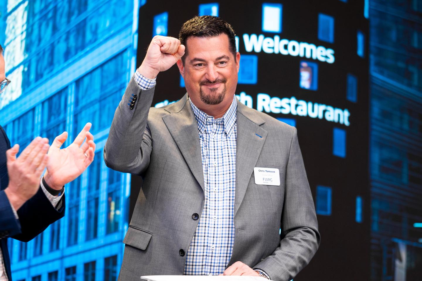 First Watch CEO Chris Tomasso holding his fist up at the New York Stock Exchange