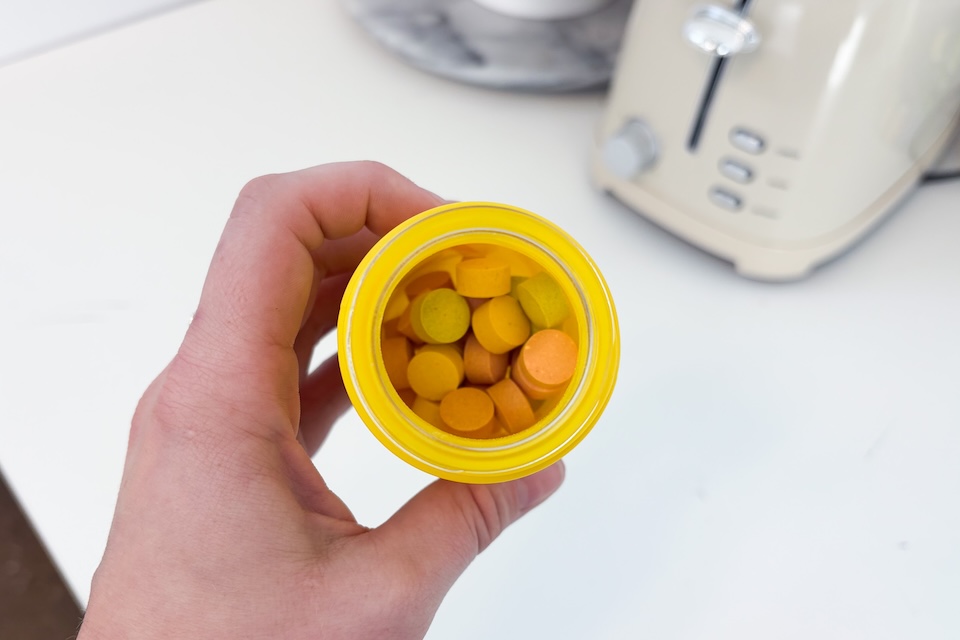 A view of an open bottle of Hiya Multivitamins from above, showing the multicolored tablets inside.