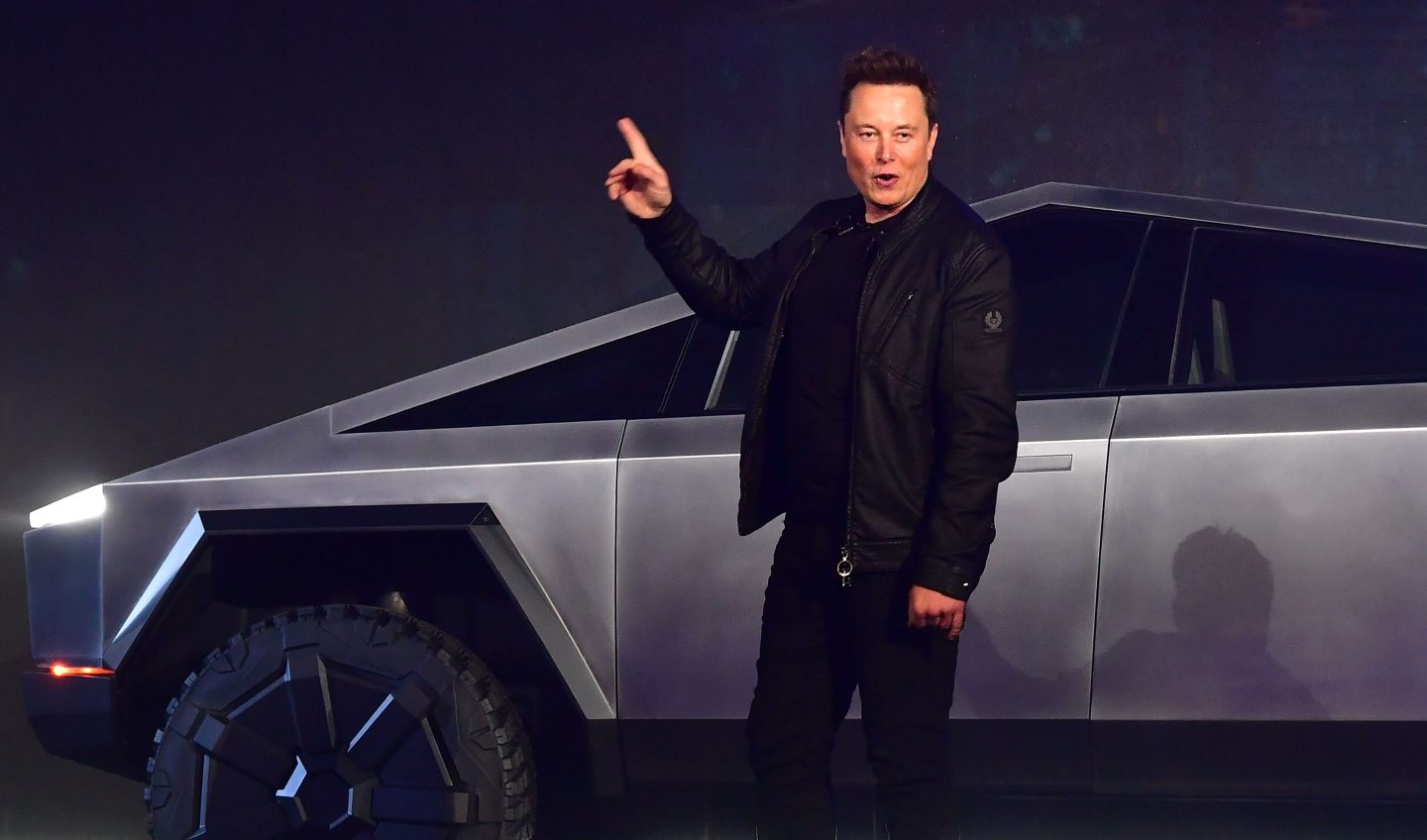 Elon Musk stands in front of a Cybertruck
