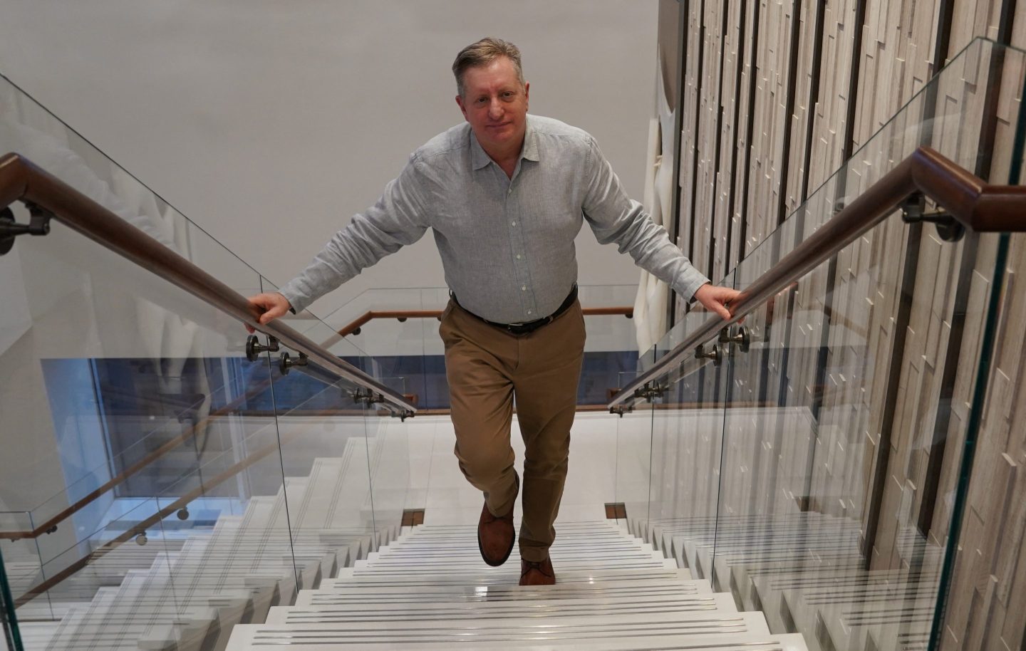 Steve Eisman walks up a flight of stairs with his hands on both sides of the railing.