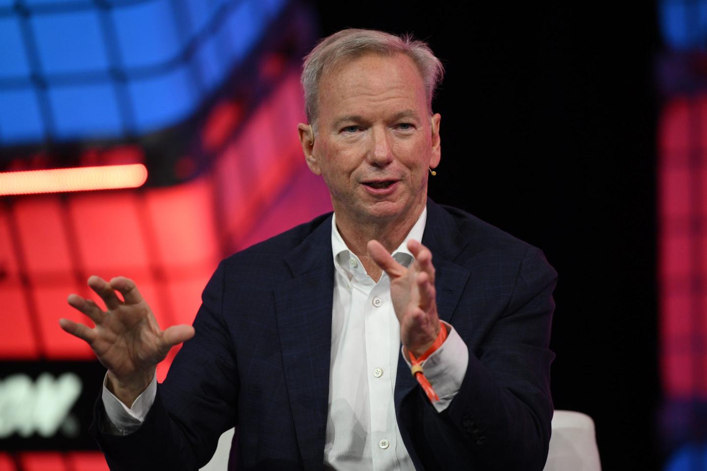 Eric Schmidt holds up his hands while speaking on stage