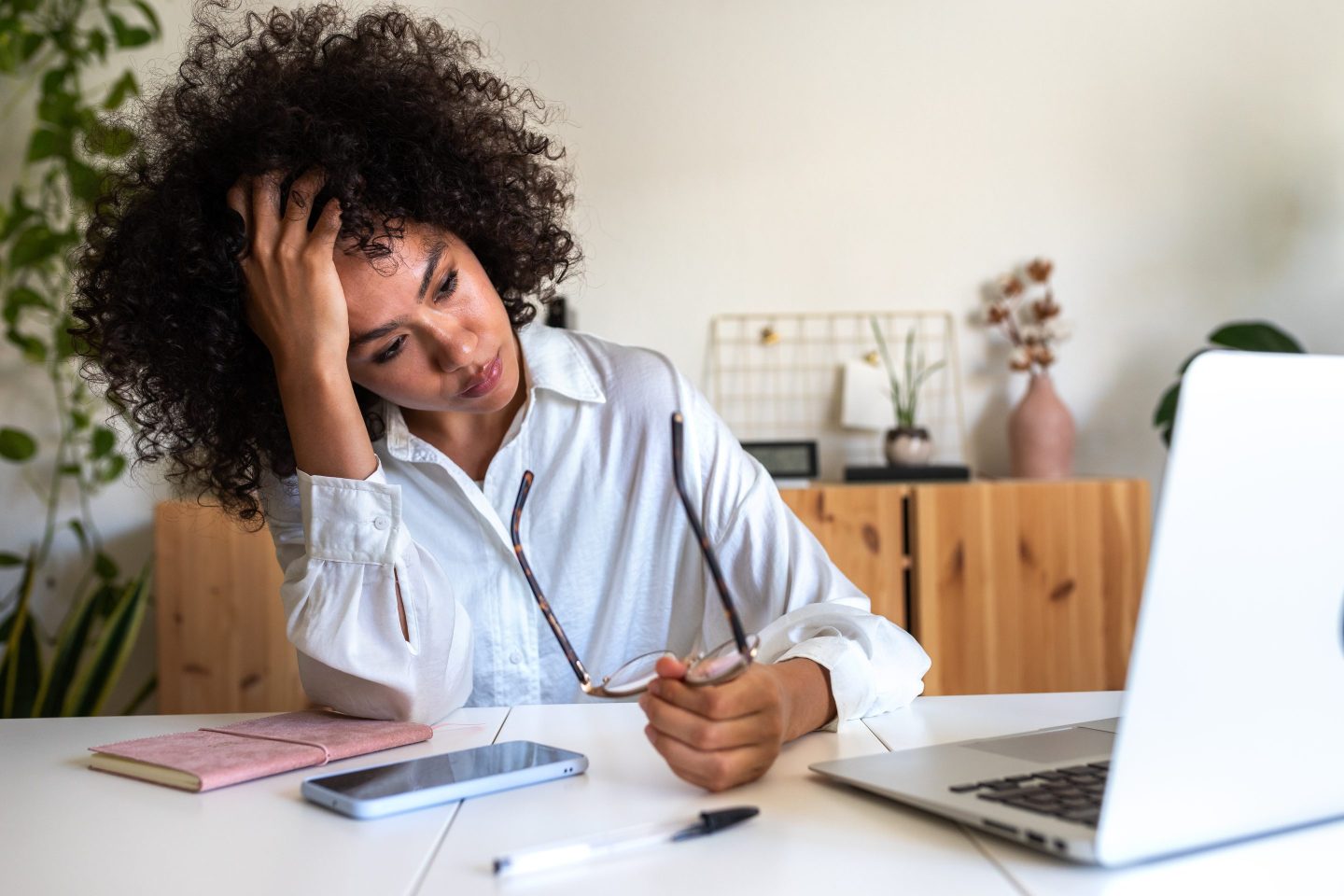 Young woman worker feeling exhausted and depressed sitting in front of laptop in office.