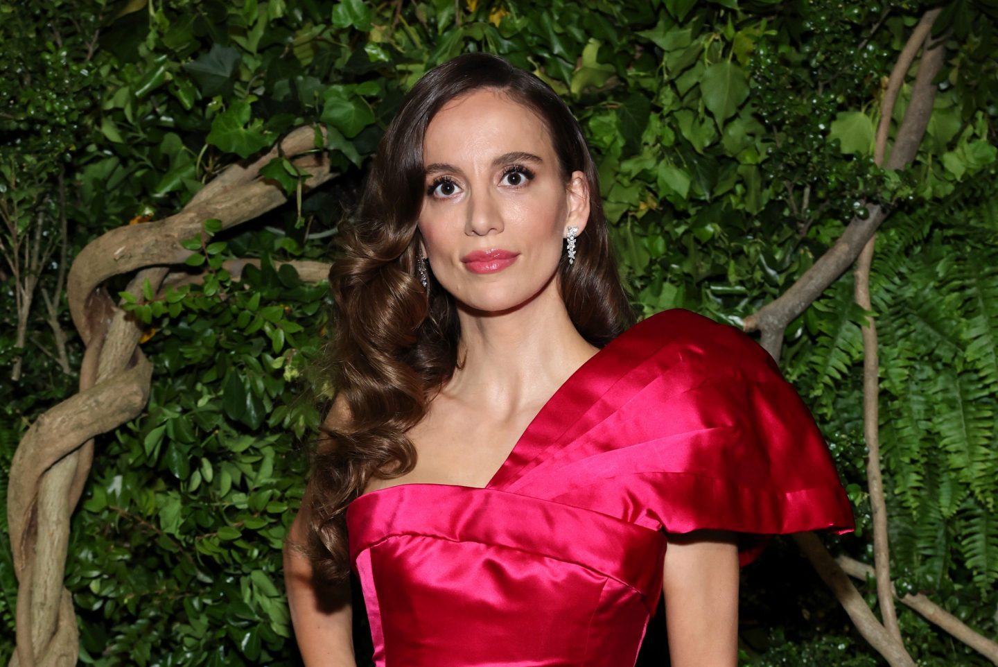 Mira Murati in a red dress in front of some trees