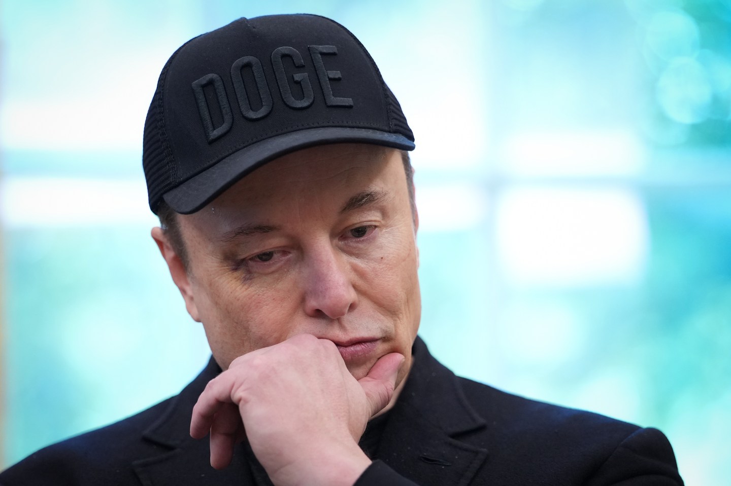 Elon Musk in a black hat and jacket