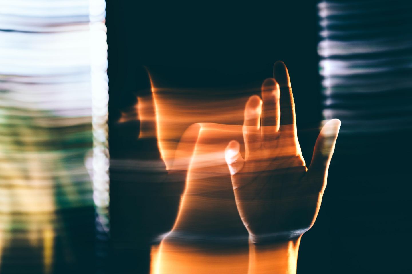 Surreal hand reaching through light trails