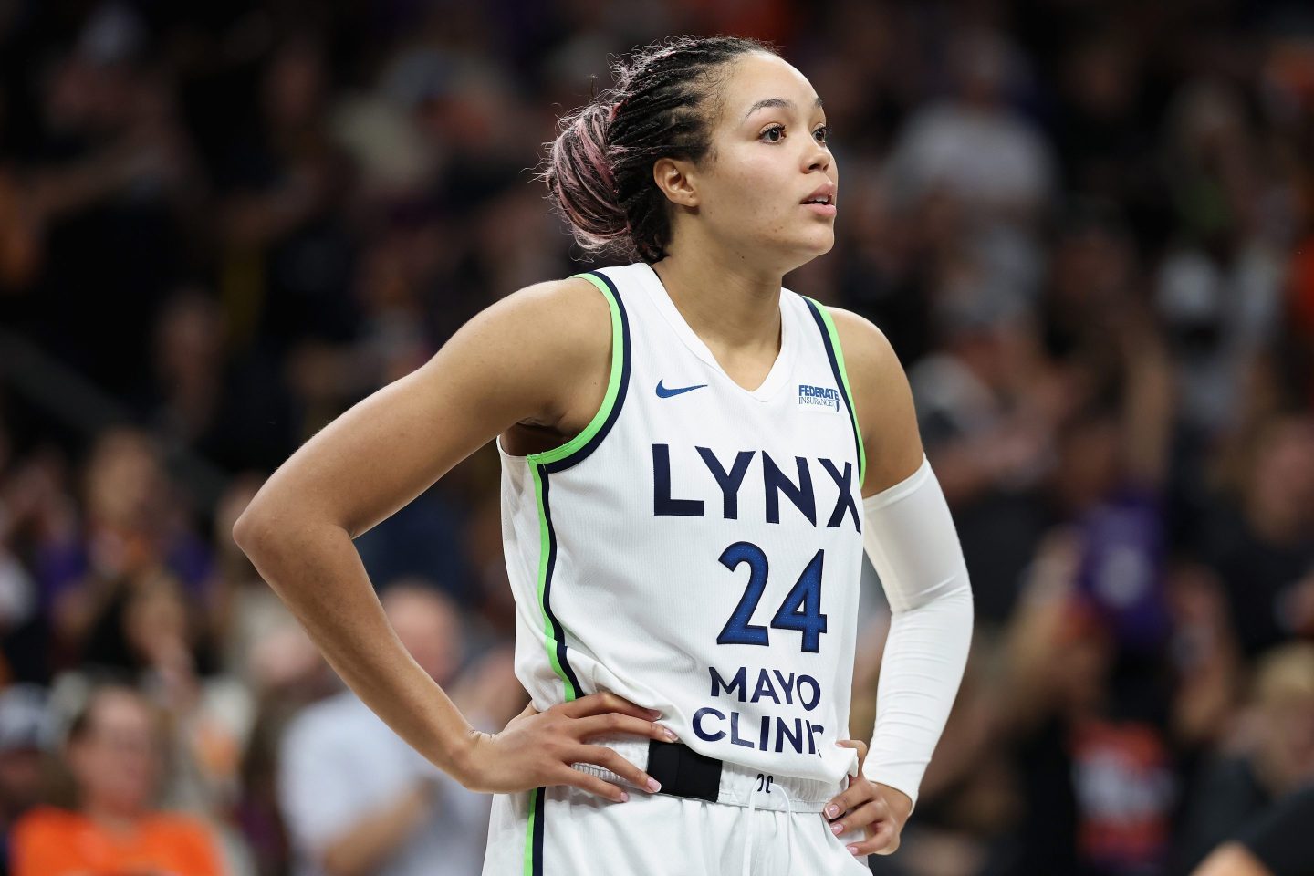 Napheesa Collier, wearing a white Lynx jersey, stands on the court with her hands on her hips.