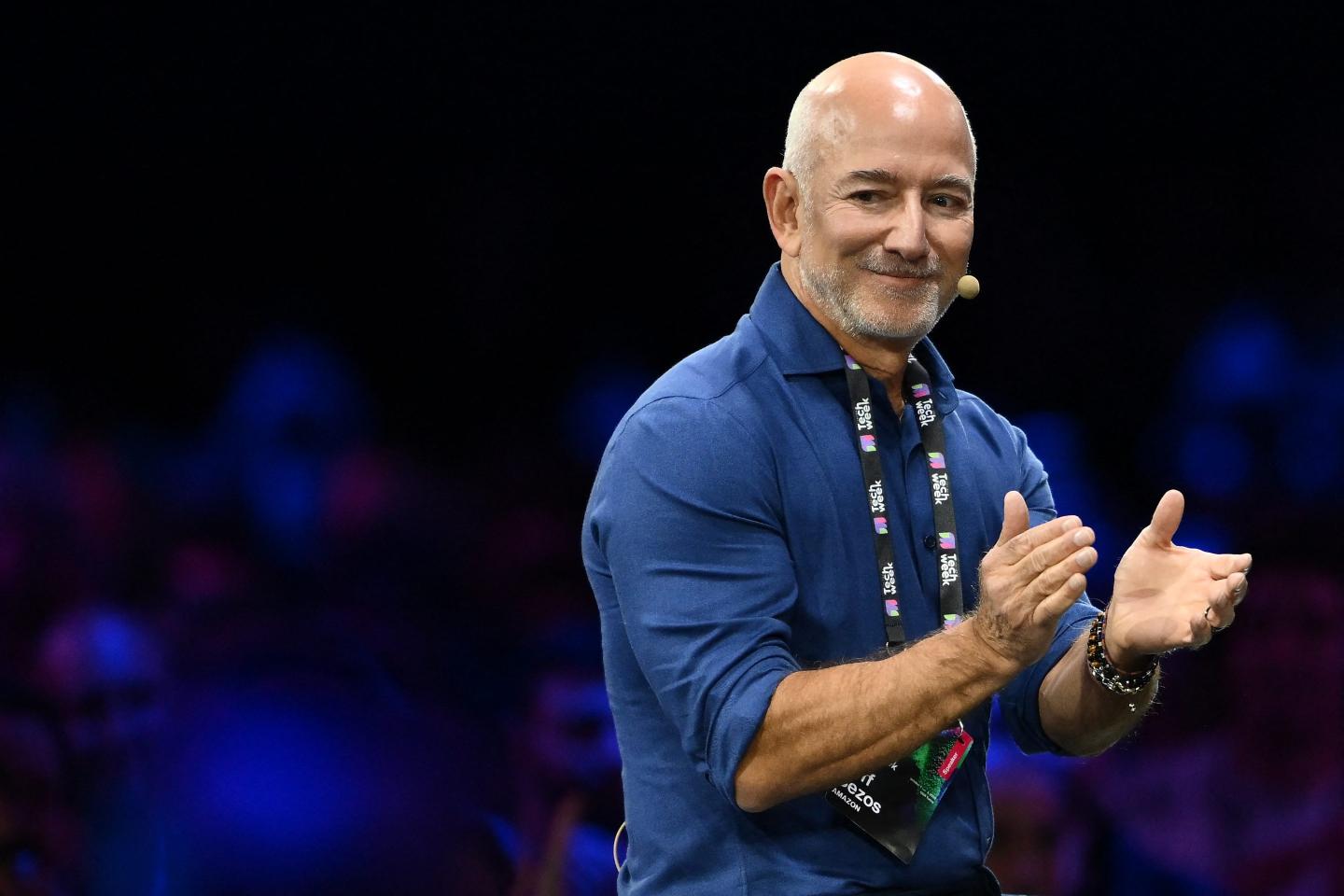 Amazon's founder Jeff Bezos applauds as he speaks with Stellantis' Chairman John Elkann on stage during the Italian Tech Week 2025, at OGR Officine Grandi Riparazioni, in Turin, northern Italy, on October 3, 2025.