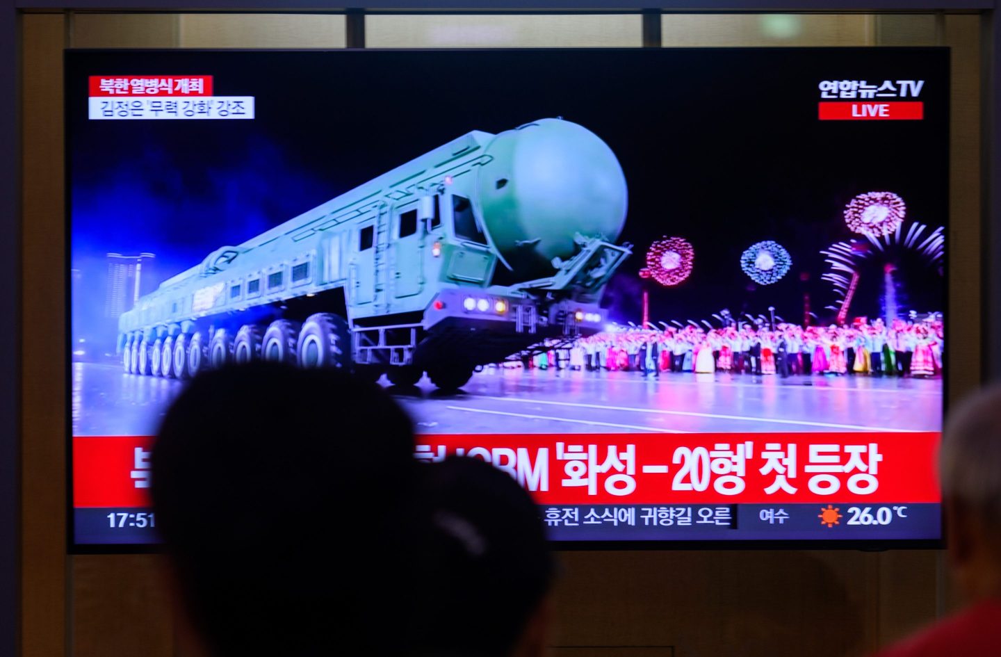 People look at a Yonhap news TV broadcast at showing a Hwasong-20 missile.