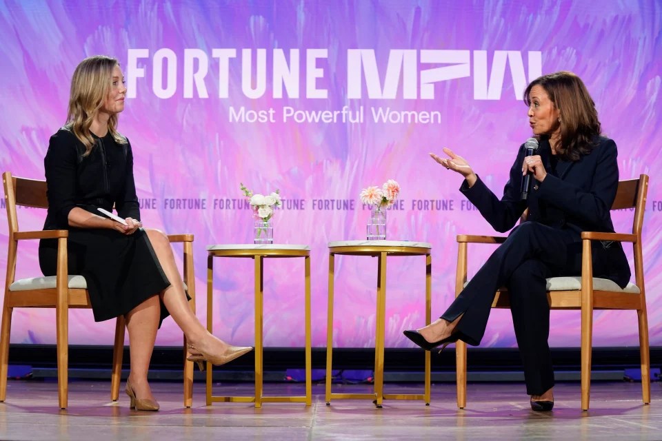 Two women in conversation in front of a screen reading "Fortune MPW"