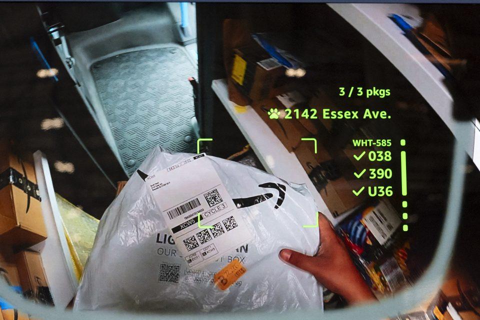A display screen of a driver looking down at a package in their hands, with green text overlaying the display.
