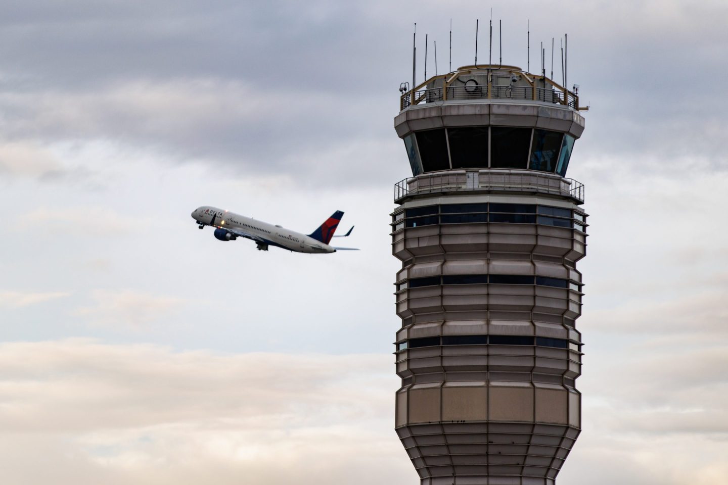 A Delta Airlines plane takes off near the air traffic control tower at Ronald Reagan Washington National Airport (DCA) in Arlington, Virginia, US, on Tuesday, Oct. 28, 2025. Transportation Secretary Sean Duffy warned that flight delays could get worse as the US government shutdown enters its 28th day and air traffic controllers miss their first full paycheck. Photographer: Samuel Corum/Bloomberg via Getty Images