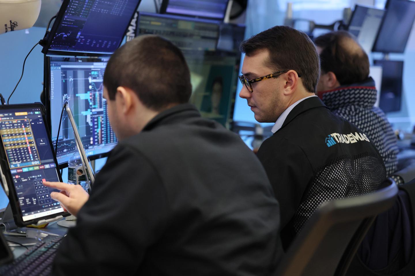 Two men are looking at monitors while trading