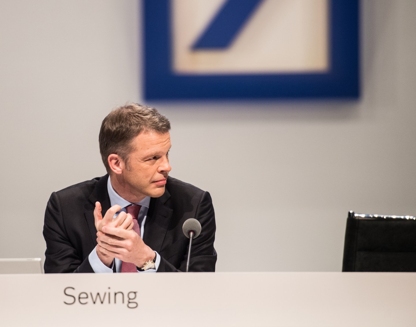 Christian Sewing sits behind a microphone