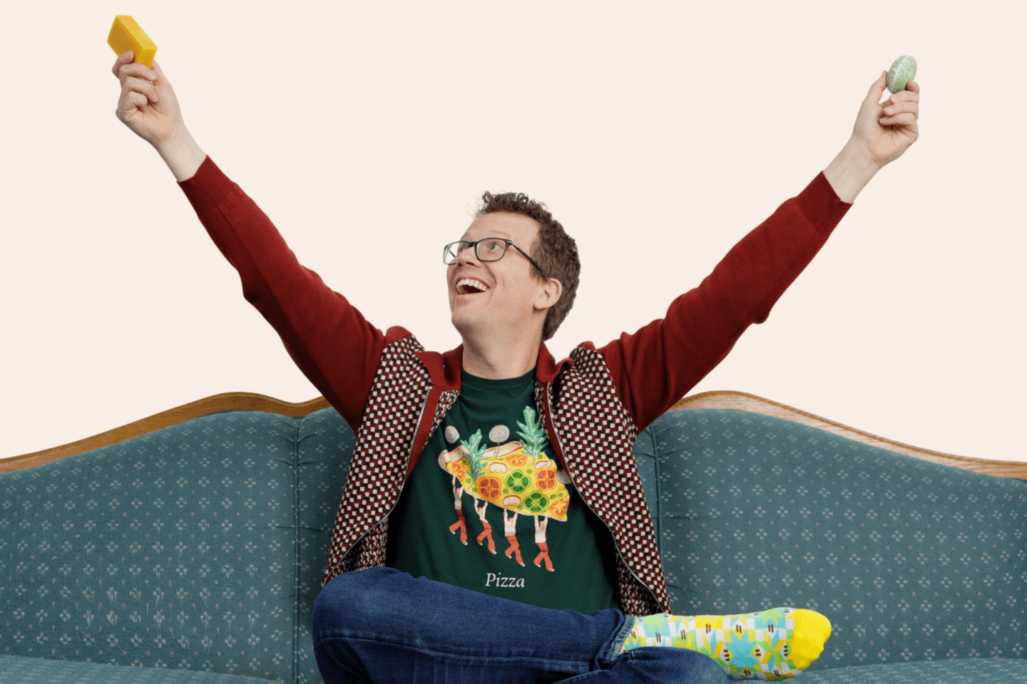 Hank Green sitting on couch holding up two bars of soap.