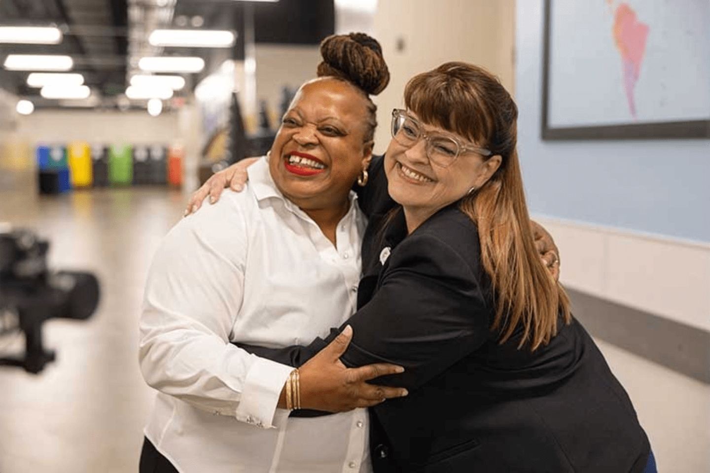 Two women hug each other in a hallway.