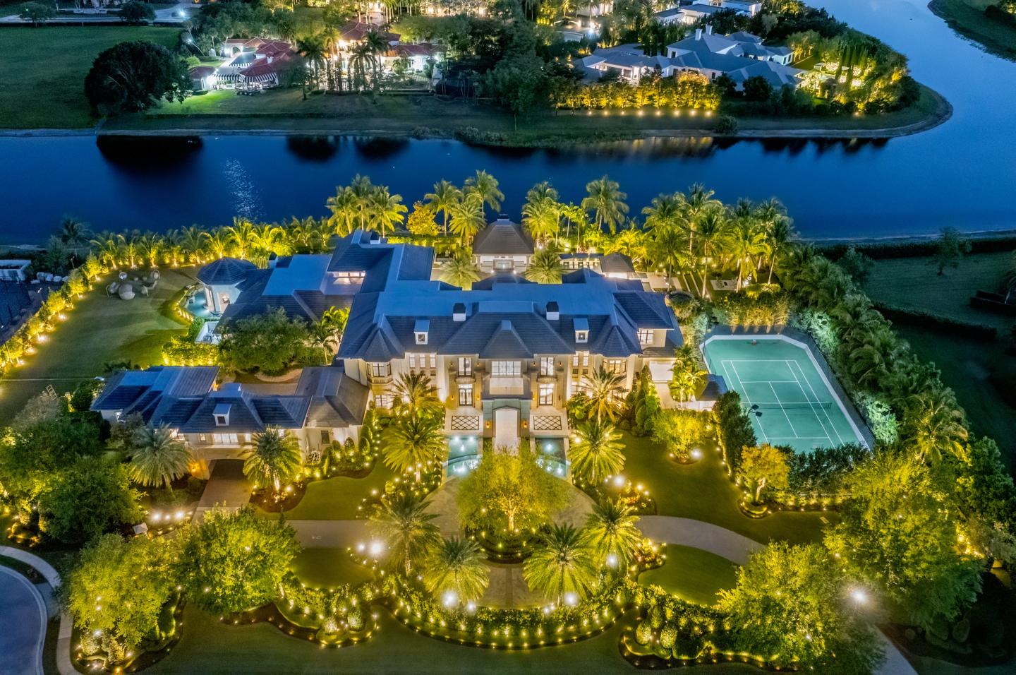 Aerial view of a huge mansion and tennis court near waterways