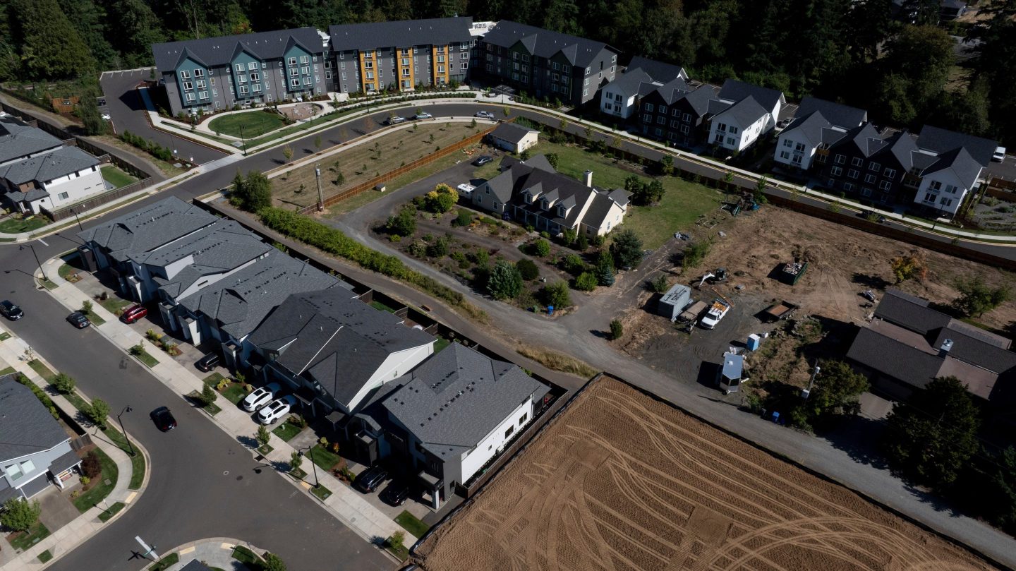 New construction homes and apartments are seen surrounding an older home on July 11, 2025, in Happy Valley, Ore.